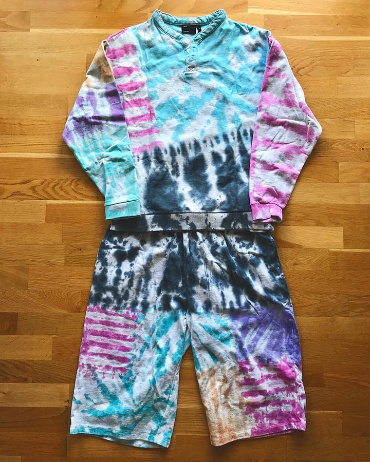 Assorted paried tye died shirts and sweat shirts with different motifs and black, turquoise, violet, pink and orange colours.