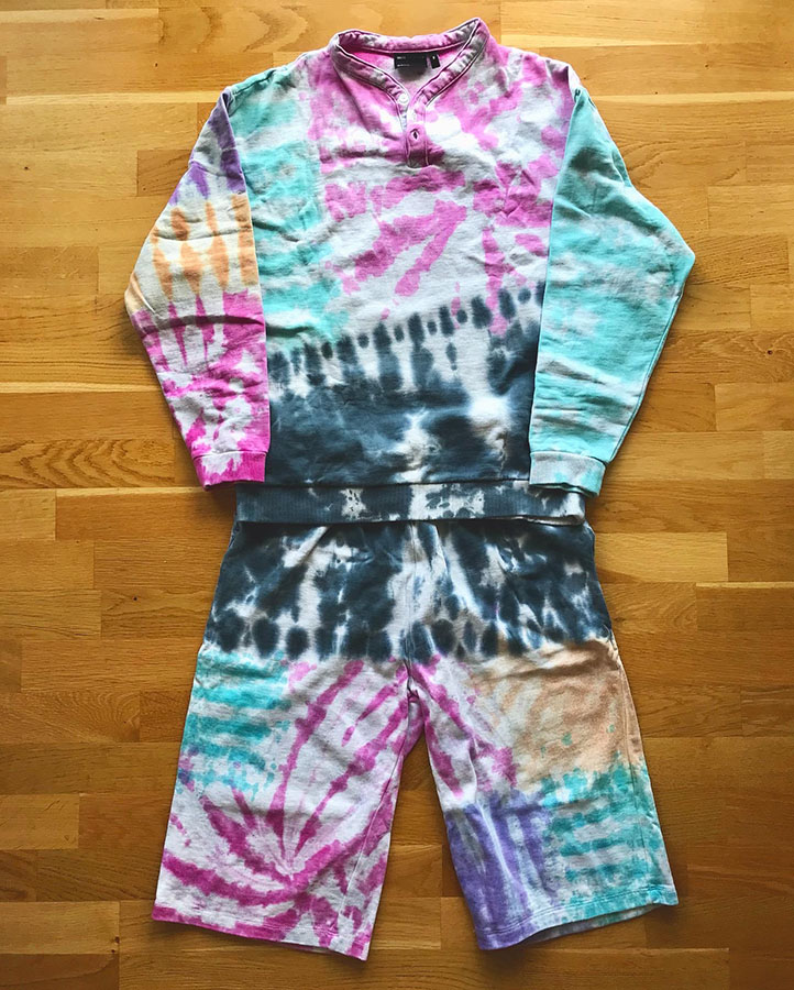 Assorted paried tye died shirts and sweat shirts with different motifs and black, turquoise, violet, pink and orange colours.